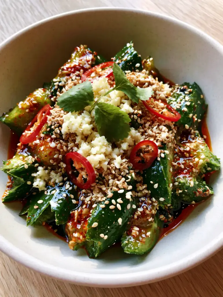 Top view of Asian cucumber salad topped with garlic, red chilies, and sesame seeds.