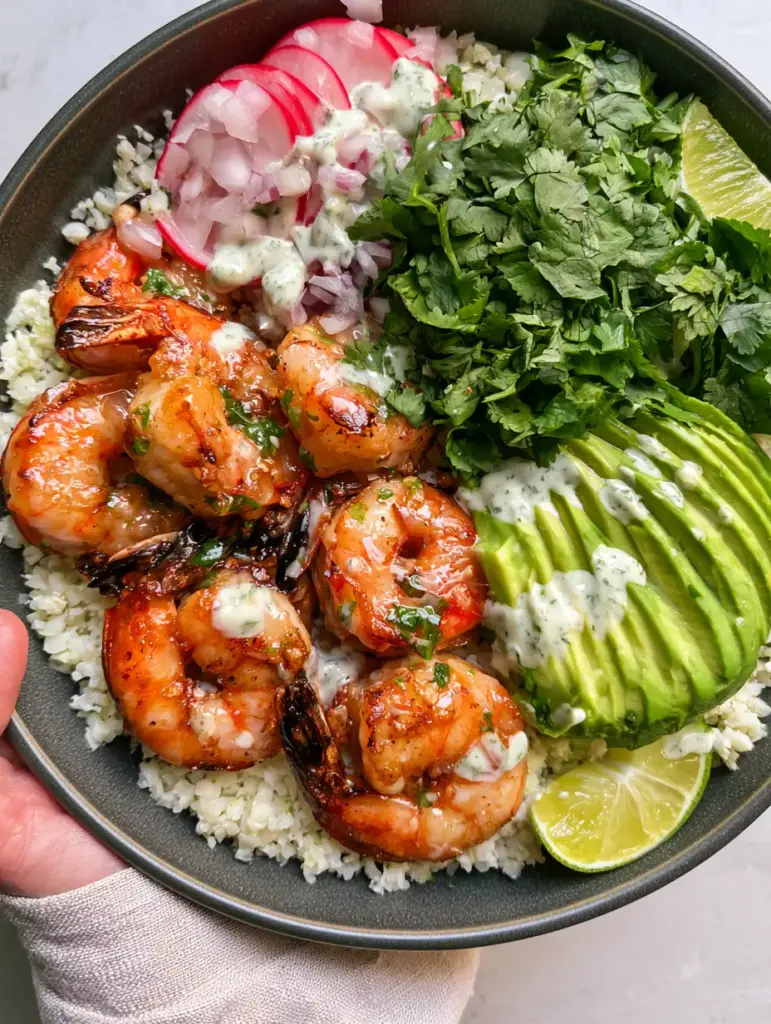Close-up of succulent shrimp with charred edges and a creamy cilantro-lime crema drizzle. (Shrimp Avocado Bowls)