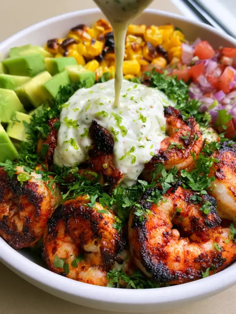 Vibrant sections of roasted corn, diced tomatoes, and cubed avocado surrounding blackened shrimp in a grilled shrimp bowl recipe.