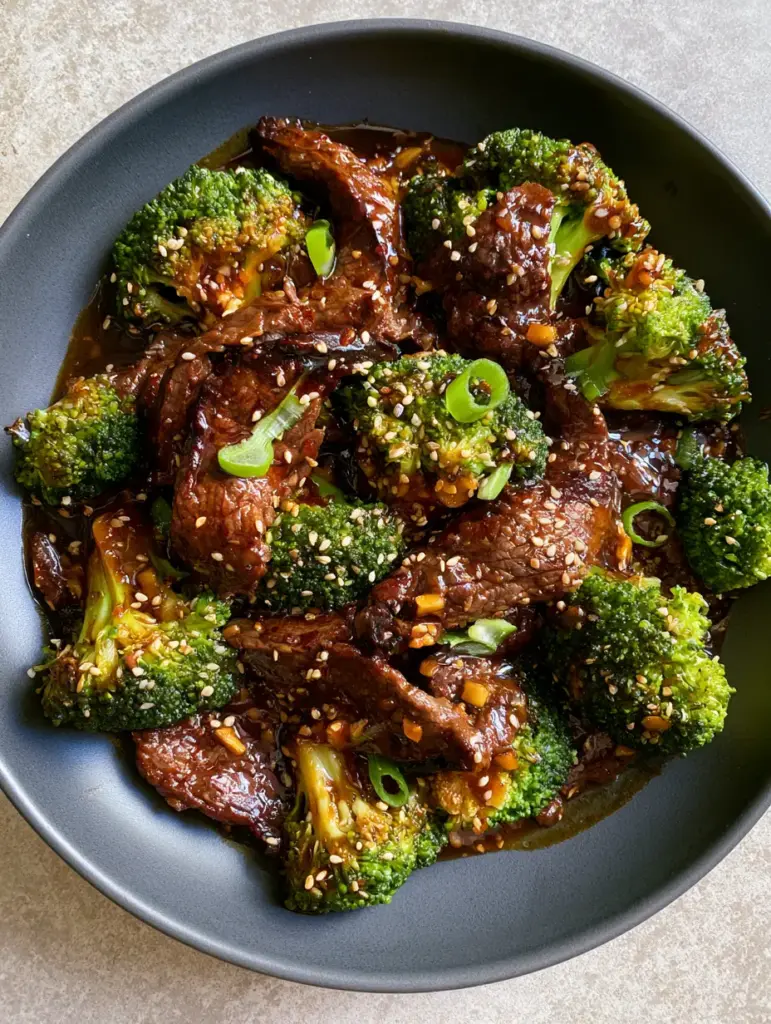 Glossy mahogany ginger-soy glaze dripping off a slice of beef and broccoli recipe.