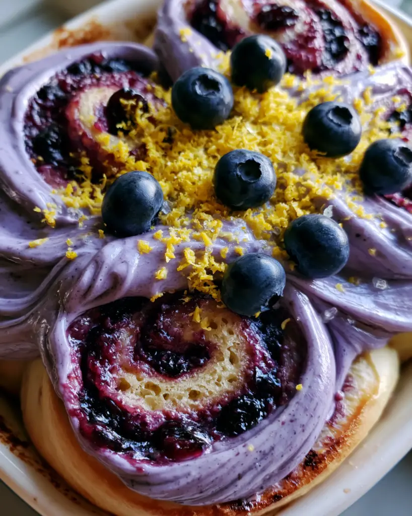 A rustic smartphone-style photo of pull-apart blueberry cinnamon rolls with lemon zest and sugar crystals.