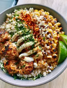 Close-up of seared cilantro lime chicken cubes with golden char and blistered corn kernels in a Street Corn Chicken Bowl.