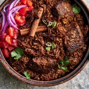 Close-up of perfectly separated basmati rice grains in a deep brown spice infusion with seared beef cubes. (East African Pilau Rice)